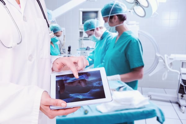 Composite image of doctor looking at xray on tablet-1